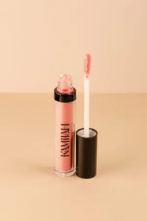 A pink lip gloss sitting next to a white tube.