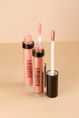 Two lip glosses sitting next to each other on a table.