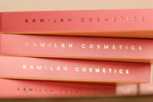 A stack of three pink books with the names of cosmetics.